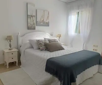 a white bedroom with a bed with a blue blanket at El balcón de Alexia, 5 minutos del aeropuerto in Partida de La Cañada