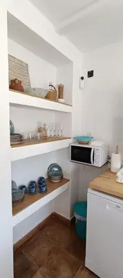 a kitchen with shelves with dishes and a microwave at Ca la Yaya in Lliria