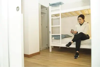 a woman sitting on a bunk bed looking at her cell phone at Aiora Hostel in Valencia