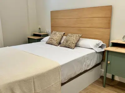 a bedroom with a large bed with a wooden headboard at El Mercado in Puerto de Sagunto
