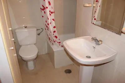 a bathroom with a white toilet and a sink at Jardin II Solo Familias Serviplaya in Playa de Xeraco