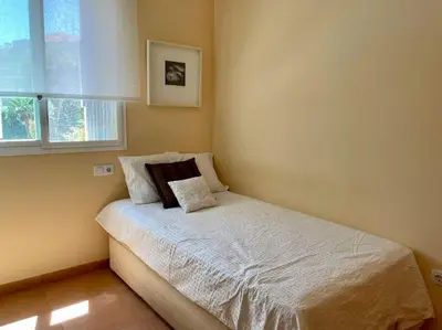 a small bedroom with a white bed with a window at Agradable adosado con piscina y jardín in Canet de Berenguer