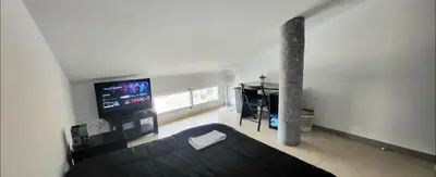 a living room with a couch and a flat screen tv at Luminoso ático dúplex con terraza de césped in Montroy