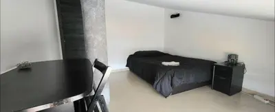 a small bedroom with a bed and a table at Luminoso ático dúplex con terraza de césped in Montroy