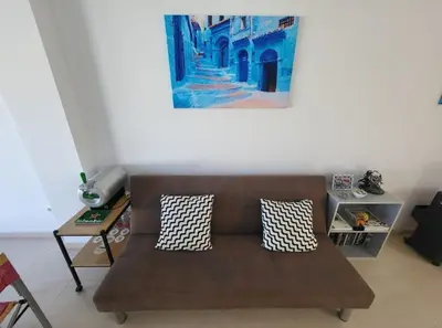 a couch in a living room with a painting on the wall at Luminoso ático dúplex con terraza de césped in Montroy