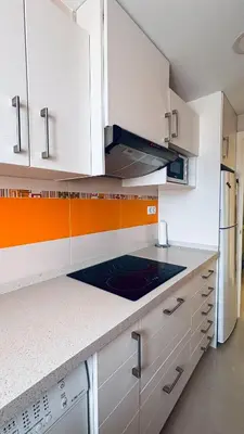 a kitchen with white cabinets and a stove top oven at Apartamento primera línea playa San Antonio in Cullera