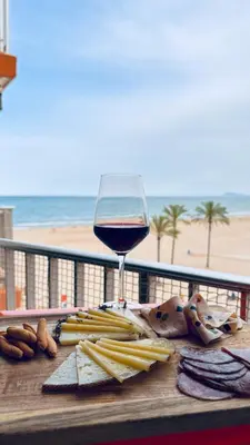 a table with a glass of wine and food on the beach at Apartamento primera línea playa San Antonio in Cullera