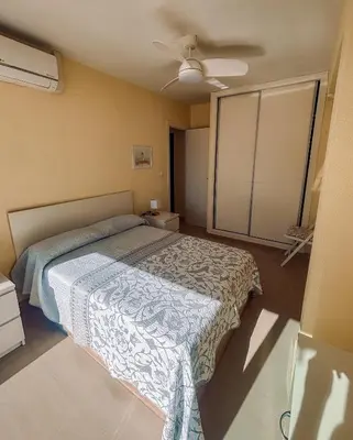 a bedroom with a bed and a ceiling fan at Apartamento primera línea playa San Antonio in Cullera