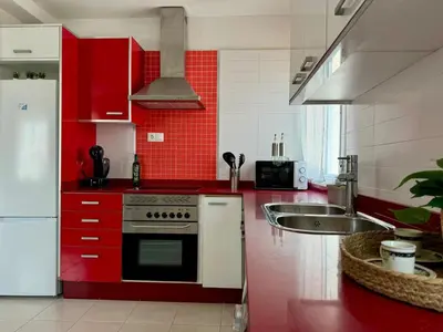 a red kitchen with a stove and a sink at Vistas al Castell de Alacuas in Alaquas