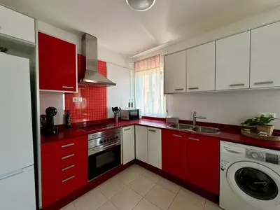 a kitchen with red cabinets and a washing machine at Vistas al Castell de Alacuas in Alaquas