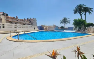 a large swimming pool in a courtyard with palm trees at Vista Mar Apartamento Playa Farnals in Playa Pobla de Farnals
