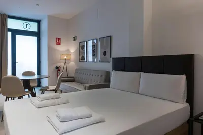 a bedroom with a large white bed and a living room at VLC HOST - Zapadores in Valencia
