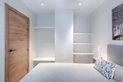 a white bedroom with a bed and a wooden door at Ruzafa´s Gate 3 in Valencia