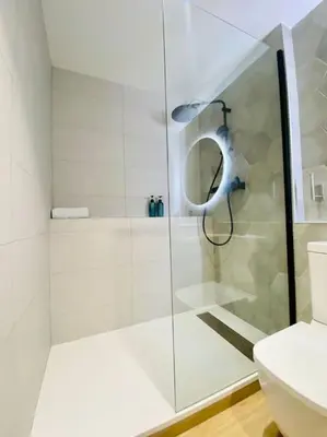 a white bathroom with a shower and a toilet at Relaxing BeachSide Cabanyal Loft in Valencia