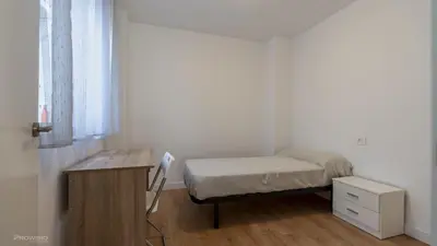 a small bedroom with a bed and a desk at Apartamentos Borriana in Burriana