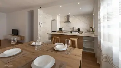 a kitchen with a wooden table with plates and wine glasses at Apartamentos Borriana in Burriana