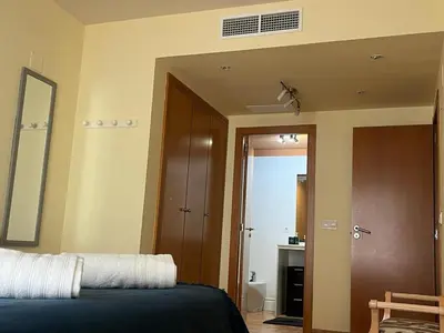 a bedroom with a bed and a mirror and a bathroom at Sea-Breeze Apartment with Pool & Parking in Cullera