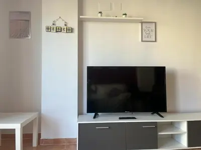 a flat screen tv sitting on top of a entertainment center at Sea-Breeze Apartment with Pool & Parking in Cullera
