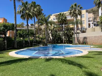 a swimming pool in a yard with palm trees at Sea-Breeze Apartment with Pool & Parking in Cullera
