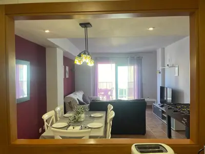 a kitchen and living room with a table and a dining room at Sea-Breeze Apartment with Pool & Parking in Cullera