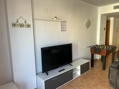 a living room with a flat screen tv and a table at Sea-Breeze Apartment with Pool & Parking in Cullera