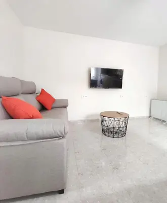 a living room with a couch and a tv on a wall at Apartamentos rurales Villamalur in Villamalur