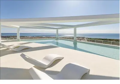 a swimming pool with white chairs and the ocean at 