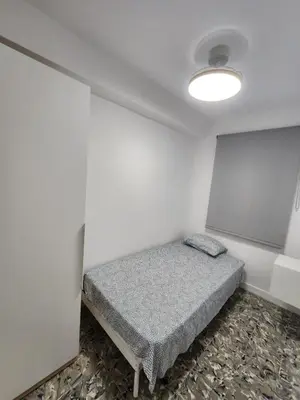 a small room with a bed and a white wall at Apartamento cerca de la playa in Cullera