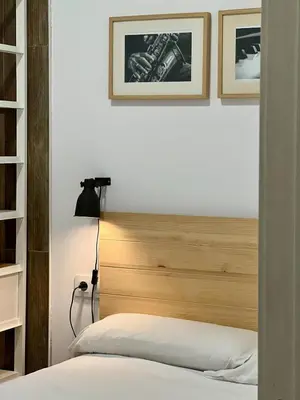 a bedroom with a wooden headboard and two framed pictures at Apartamentos de Pradas in Valencia