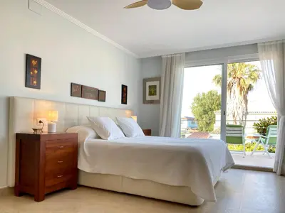 a white bedroom with a bed and a sliding glass door at Cullera Valencia Escapada de ensueño in Valencia