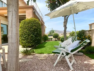 two lawn chairs and an umbrella next to a house at Cullera Valencia Escapada de ensueño in Valencia