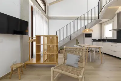 a living room with a staircase and a table and chairs at ApartUP Ca La Leni Beach V in Valencia
