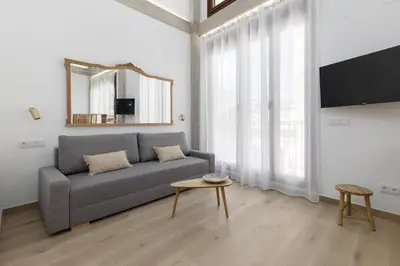 a living room with a gray couch and a mirror at ApartUP Ca La Leni Beach V in Valencia