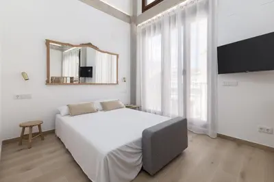 a white bedroom with a large bed and a mirror at ApartUP Ca La Leni Beach V in Valencia