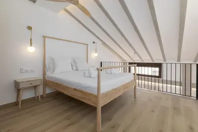 a bed in a room with white walls and wood floors at ApartUP Ca La Leni Beach V in Valencia