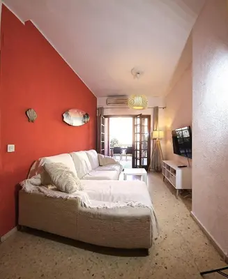 a living room with a couch and a red wall at Vacansis Port Saplaya 2 in Port Saplaya