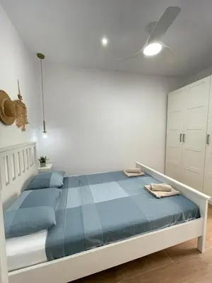 a white bedroom with a bed with blue sheets at UIM Mediterraneo CASA Gomez Ferrer Wifi in Puerto de Sagunto