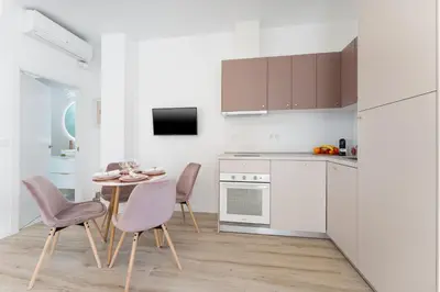 a white kitchen with a table and chairs and a tv at SOHO BY THE SEA Valencia in Valencia