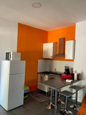 a kitchen with a white refrigerator and an orange wall at El Refujio maison independante avec vraie piscine privée au sel chauffee pas de chlore in Turís