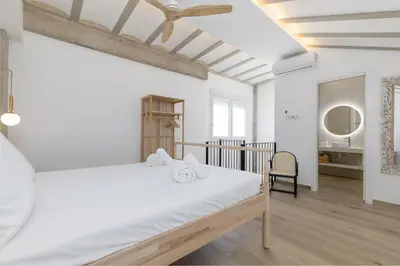 a white bedroom with a bed and a chair at ApartUP Ca La Leni Beach IV in Valencia