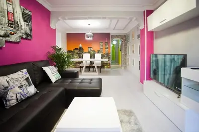 a living room with a black couch and a pink wall at 4-Bed Sleeps 7 Free Parking in Valencia