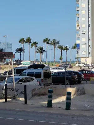 a parking lot at the beach with cars and palm trees at Casa Vistalmar in Cullera