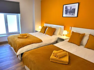 two beds in a room with orange walls at NUEVO Apartamentos Costa del Alma in Valencia
