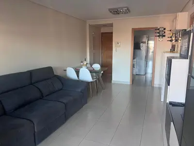 a living room with a blue couch and a table at APARTAMENTO Playa Patacona VALENCIA in Valencia