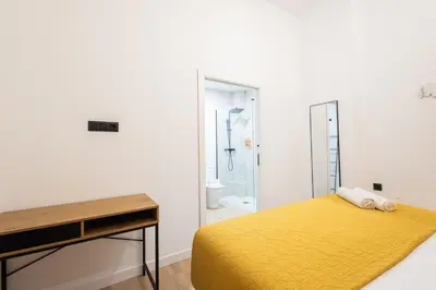 a bedroom with a yellow bed and a bathroom at The Blasco Ibañez Apartments in Valencia