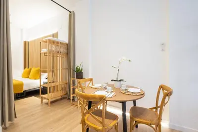 a dining room with a table and chairs and a bed at The Blasco Ibañez Apartments in Valencia