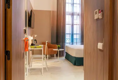 a room with a bed and a desk and a bed and a table at Axel Hotel Valencia - Adults Only in Valencia