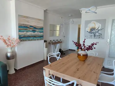 a dining room with a wooden table with a vase on it at Euromar Playa Cullera frente al mar con garaje in Cullera