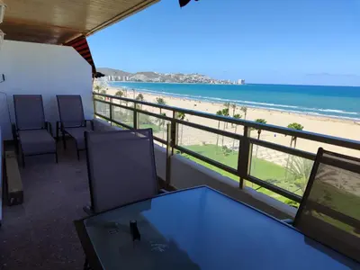 a balcony with a table and chairs and a beach at Euromar Playa Cullera frente al mar con garaje in Cullera