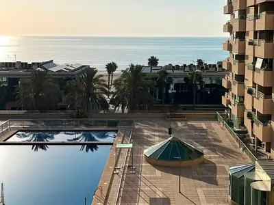 a swimming pool with an umbrella next to a building at Stylish well-connected beachfront flat in Valencia